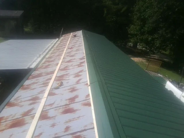 Old rusted panels beside newly installed green metal roofing — Wind Damage Roof Repair by Roofing Brothers in The Villages