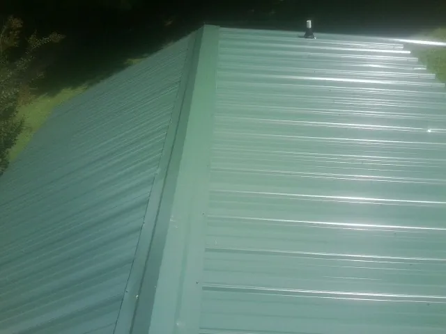 New green metal panels meeting at the ridge of a roof — Flat Roof Repair work by our crew in The Villages