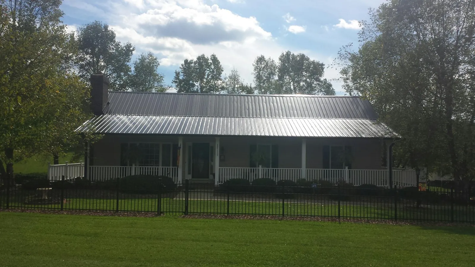 Gray metal roof on a brick ranch with a full width front porch — Gutter Guard Installation work by our crew in The Villages
